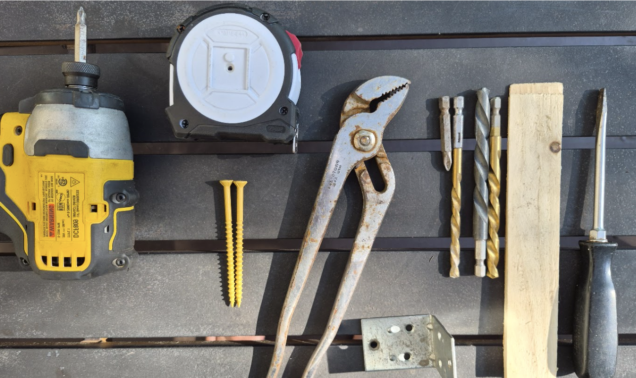Garden improvement tools including a drill, tape measure, pliers, drill bits, screws, wood, and a screwdriver laid out for a project.